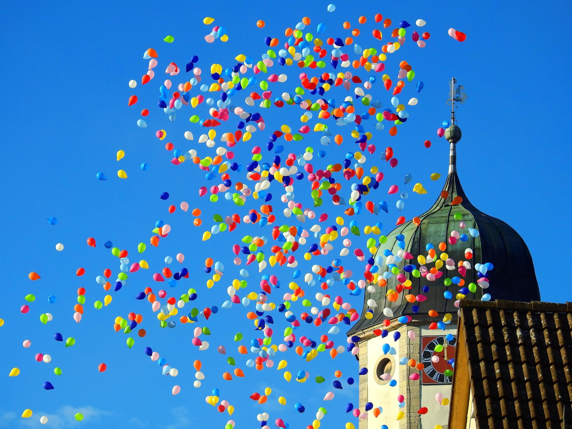 Aufsteigende Ballons vor einem Kirchturm