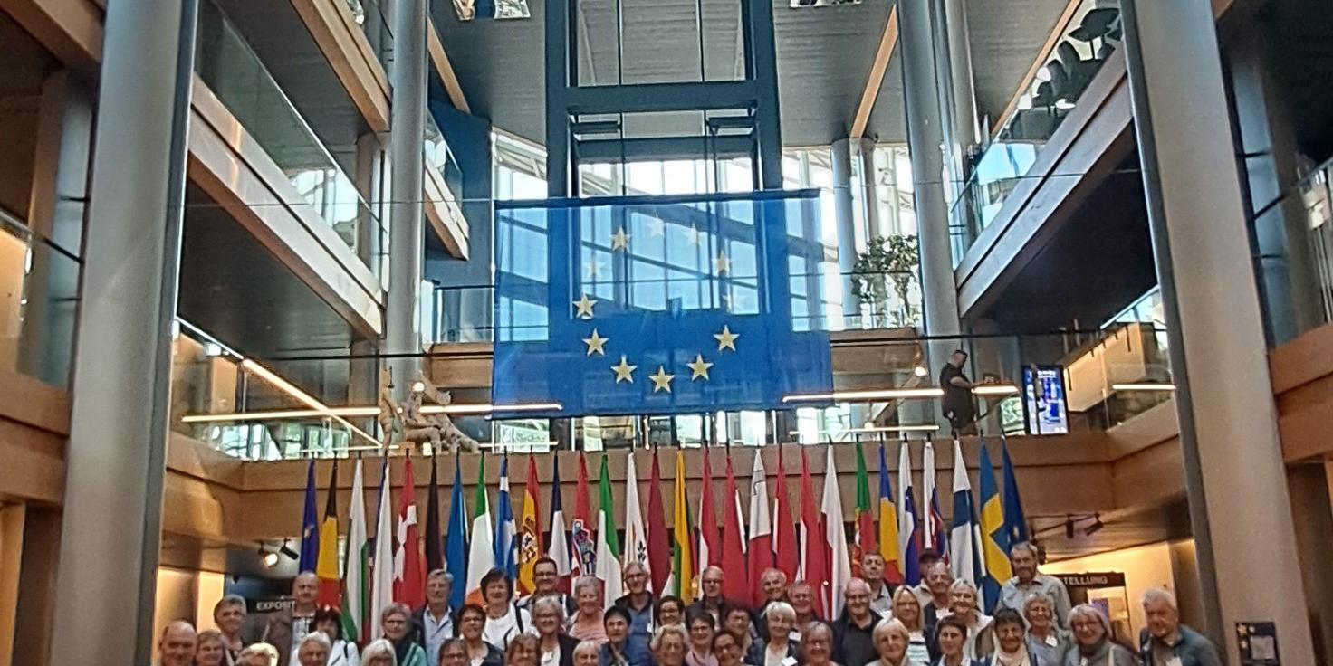 Pfarrfahrt 2026_1 Die Reisegruppe vor den Flaggen der Mitgliedsstaaten der Europäischen Union
