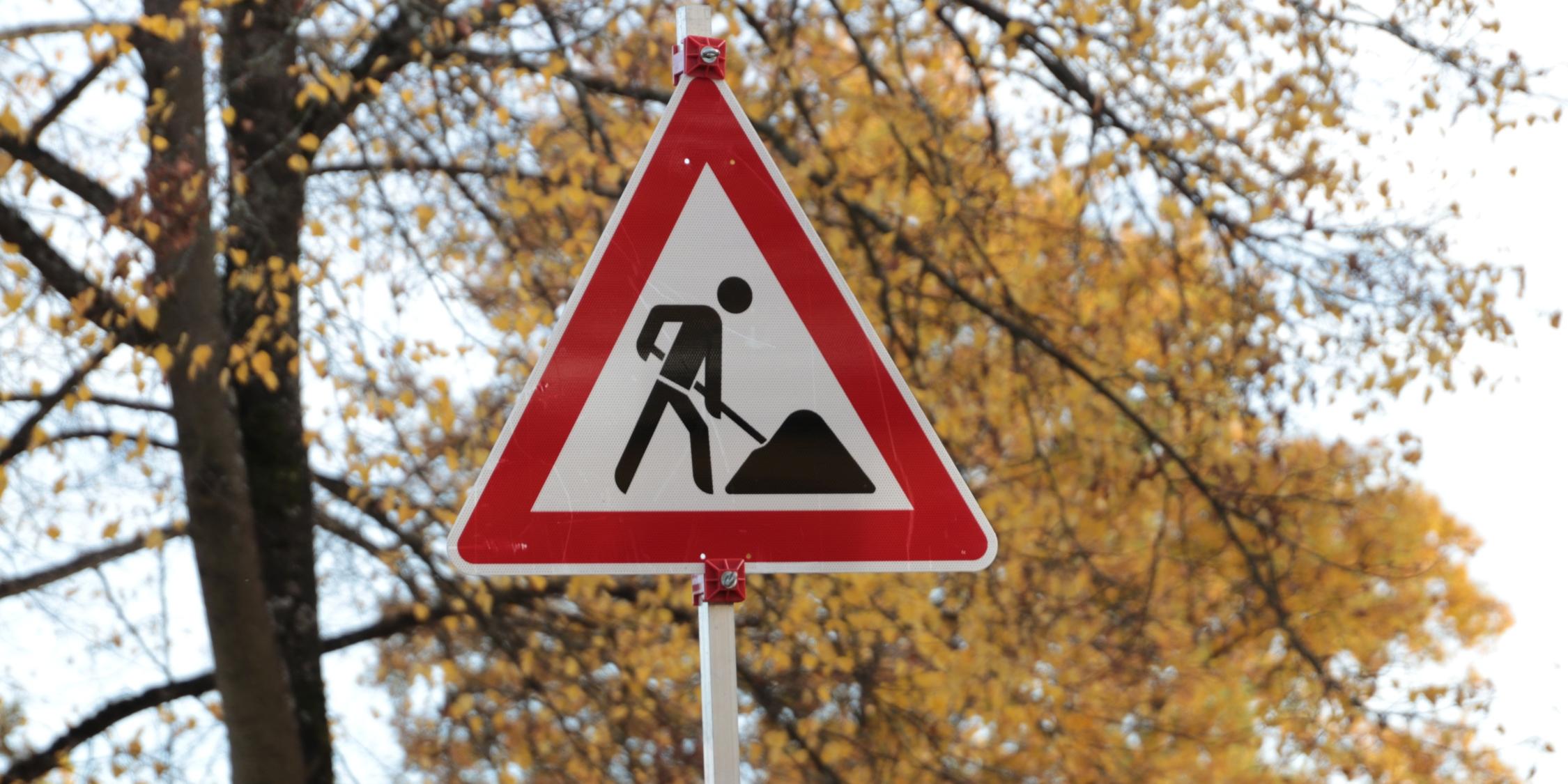Verkehrsschild Baustelle vor herbstlichen Bäumen
